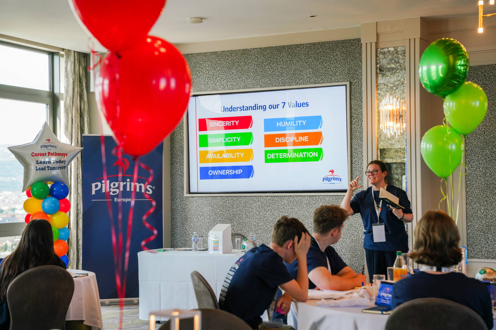 Person giving a talk to audience gathered round tables